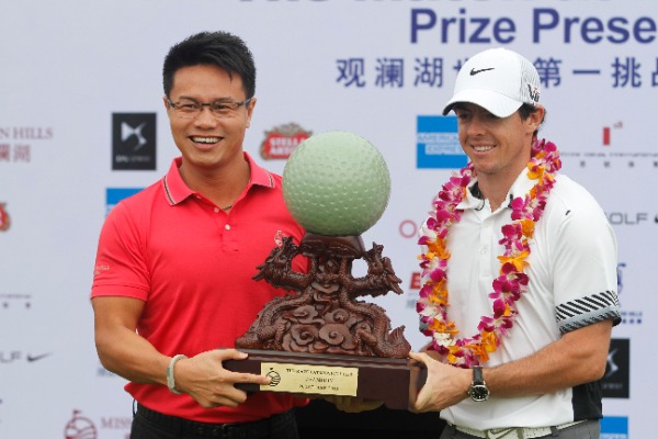 Rory McIlroy of Northern Ireland, right, receives the champion trophy at the award ceremony of The Match at Mission Hills in Haikou city, south Chinas Hainan province, 28 October 2013